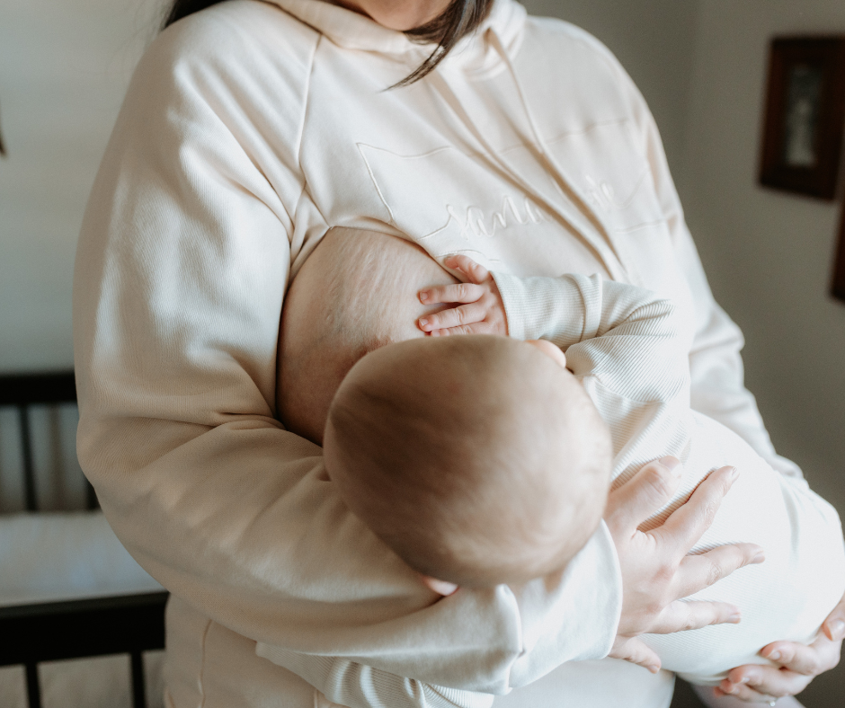 Woman breastfeeding baby in the SanaLove Hoodie.